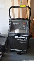 Full view of the DieHard battery charger and engine starter, showing handle, front display panel, and attached cord.