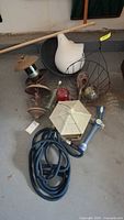 Lot contents showing multiple bird feeders, a white ceramic bird decoration, a coiled blue garden hose, and a small birdhouse with hexagonal design.