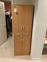 Full view of closed pressed wood cabinet standing against wall.