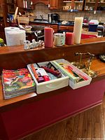Candle lot displayed on wood counter showing candles, candle holders, magazines, and small organizers with personal items.
