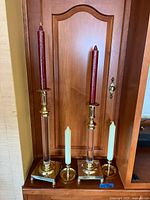 Two sets of candle holders, tall brass & glass with red candles, smaller brass with white candles.