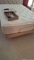 Full view of adjustable bed base with quilted mattress top and box including supplies on top.