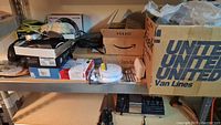 Shelf with various electrical items including boxed supplies, wires, and alarm clocks