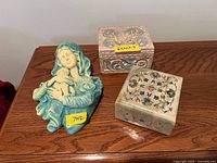 Photo showing two decorative boxes and a Madonna and Child sculpture displayed on a wooden table.