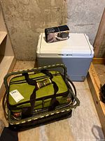 Photo of entire lot showing the Coleman electric cooler, picnic baskets including green insulated soft cooler/bag, and the thermoelectric adapter box resting on cooler lid.