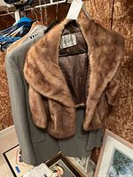Gray men's suit jacket with brown mink stole hanging on a hanger.