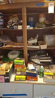 Photo showing shelves filled with various hardware boxes including nails, tape rolls, tubing and small containers of fasteners.