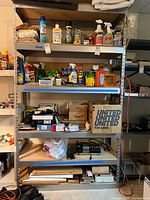 Front view of heavy duty metal framed shelf loaded with various household items and cleaning supplies (not included).