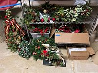 Wide angle photo showing multiple items including decorated holiday trees, assorted wreaths, greenery on shelves, and an artificial reindeer figure decorated with holiday elements.