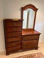 Front view of the nine-drawer chest of drawers with attached arched mirror. Medium brown wood finish with brass handles. Light surface wear visible.