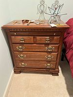Front view of Kincaid wooden side stand with decorative brass handles and various small decorative objects on top.