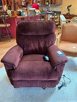 Front view of burgundy La-Z-Boy power recliner chair with remote on seat, showing plush padded arms and backrest