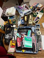 Overview of all loose office supplies on a table showing scissors, tape, clips, stapler, markers, and other small items.
