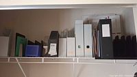 Shelf with assorted file organizers including magazine holders, file boxes, and document sorters, also containing some file folders and papers.