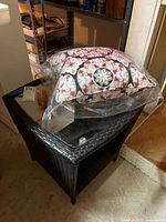 Side table shown topped with packaged outdoor pillow. Dark all weather wicker with glass top square at around 20x20x19".