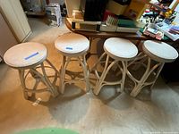 Photo of all four rattan stools, showing the full set with consistent design and one stool marked as shortened.