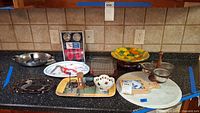 Full view of counter with various kitchen and seafood utensils, serving trays, marble board, and bowls