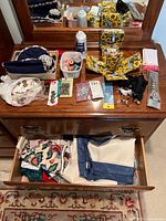 Full view of dresser top and drawer showing assorted sewing kits, fabric pieces, and sewing notions with some black curtain rings