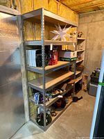 Full view of metal shelving unit with items on some shelves showing its structure and size in basement area.