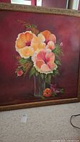 Framed signed painting of floral arrangement featuring yellow, orange, and pink flowers in a vase against a dark burgundy background.