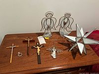 Photo showing three stained glass angel figurines and three crucifixes on wooden surface