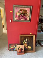 Four oil on canvas still life paintings arranged near a red wall, two framed large paintings and two smaller unframed paintings.