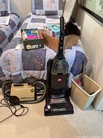 Hoover upright vacuum, Eureka canister vacuum, attachments, vacuum bags in box and bin next to beds.