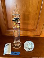 Full view of Galileo thermometer and Waterford crystal clock with tags and measuring tape