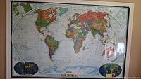Front view of the large pinned world map poster on the wall with visible countries and geographical details.