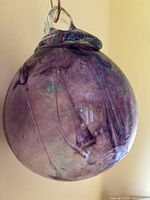 Front view of purple hand-blown glass ornament showing internal ribbons and bubbles