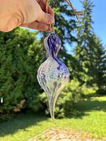 Ornament held outdoors showing purple and white swirl pattern and shape