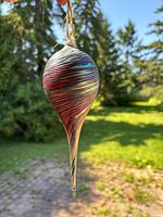 Full view of ornament hanging outdoors showing teardrop shape and colors