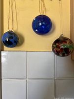 Three hanging hand-blown glass balls, two cobalt shades and one multicolour