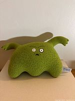 Front view of green Monster Factory El Niño plush toy showing face and arms
