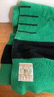Label on green wool blanket showing Hudson's Bay Company crest and 100% wool, made in England