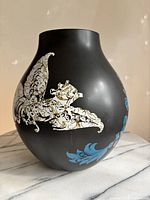 Front view showing black ceramic body and white/gold floral motif