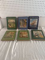 Six 'My Book House' children's books displayed on a shelf, showing front covers featuring vintage illustrations of children, animals, and outdoor scenes from the 1954 series.