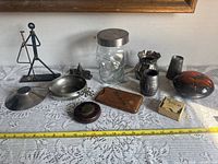 Photo showing the entire lot of collectible items arranged on a lace tablecloth including figurine, bowls, glass jar, boxes, and small decorative pieces.