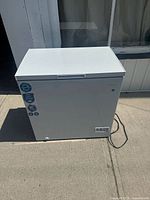 Front view of white Danby chest freezer on concrete, showing brand and condition.