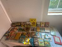 Wide shot showing the entire collection of vintage young adult and children's books spread across a table.