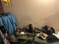 Full view of assorted reenactment clothing including blue coat, boots, helmets, hats, military gear spread on table and floor