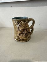 Front view showing sculptural face and unique handle of ceramic mug