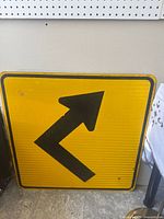 Front view of the square metal road sign showing the right turn arrow on a yellow background.