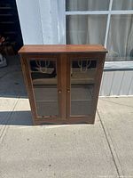 Front view of the wooden bookcase showing two glass doors and wood finish.