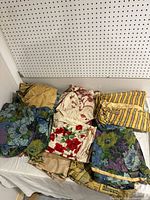 Assortment of folded vintage fabrics and curtains showing various floral and striped patterns.