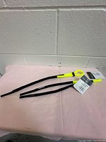 Two neon yellow and black floating eyewear cords with retail hang tags on pink surface