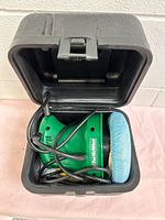 Buffer-polisher placed inside hard case showing cord and pad