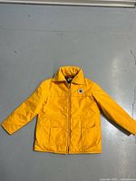 Full front view of yellow Mustang flotation jacket laid flat