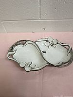 Top view showing twin white bowls, silver rim, flower accents