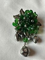 Front view of brooch showing green glass bead cluster and dangling silver-tone beads
